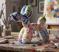 Colorful balloon dog sculpture on a table with art supplies in a studio setting