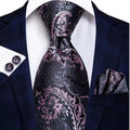 Navy suit with a black and pink paisley tie, pocket square, and cufflinks on a white background