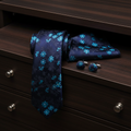 Navy floral tie, pocket square, and cufflinks on a wooden drawer
