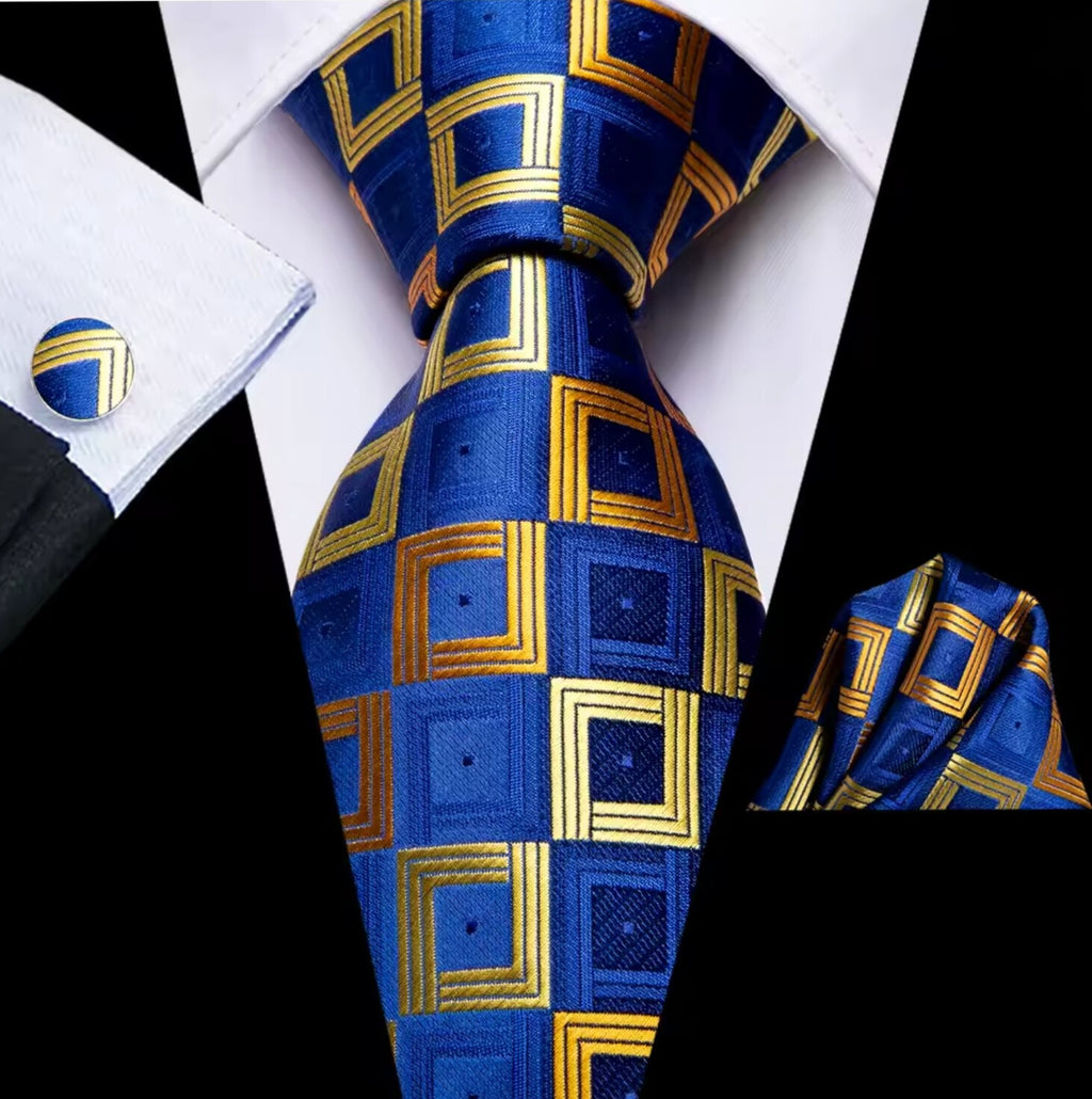 Blue and gold checkered tie with matching pocket square and cufflinks on a white shirt.