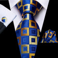 Blue and gold checkered tie with matching pocket square and cufflinks on a white shirt.