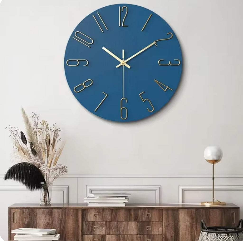 Blue wall clock with gold numbers on a white wall above a wooden console table.