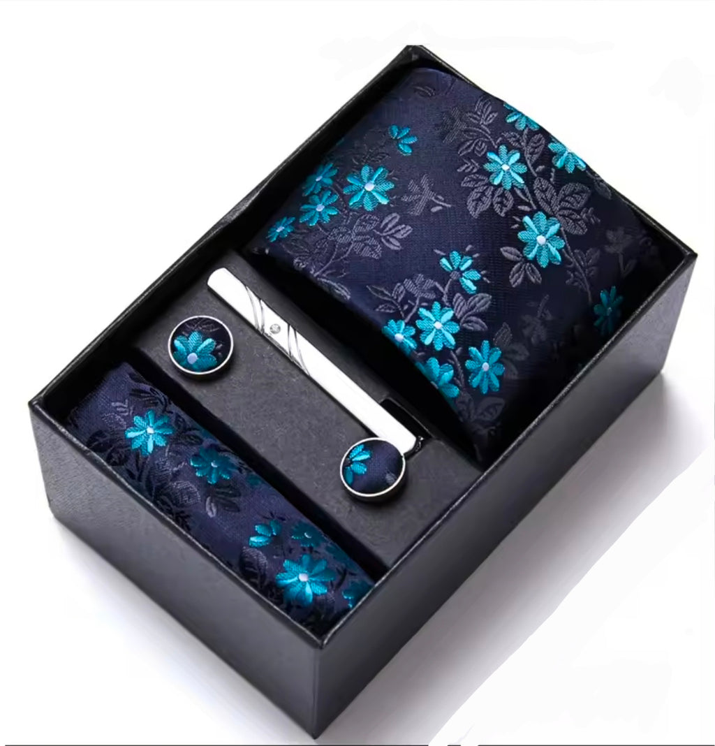 Floral patterned tie set with pocket square and cufflinks in a black box on a white background