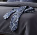 Blue paisley tie and cufflinks on a dark fabric surface