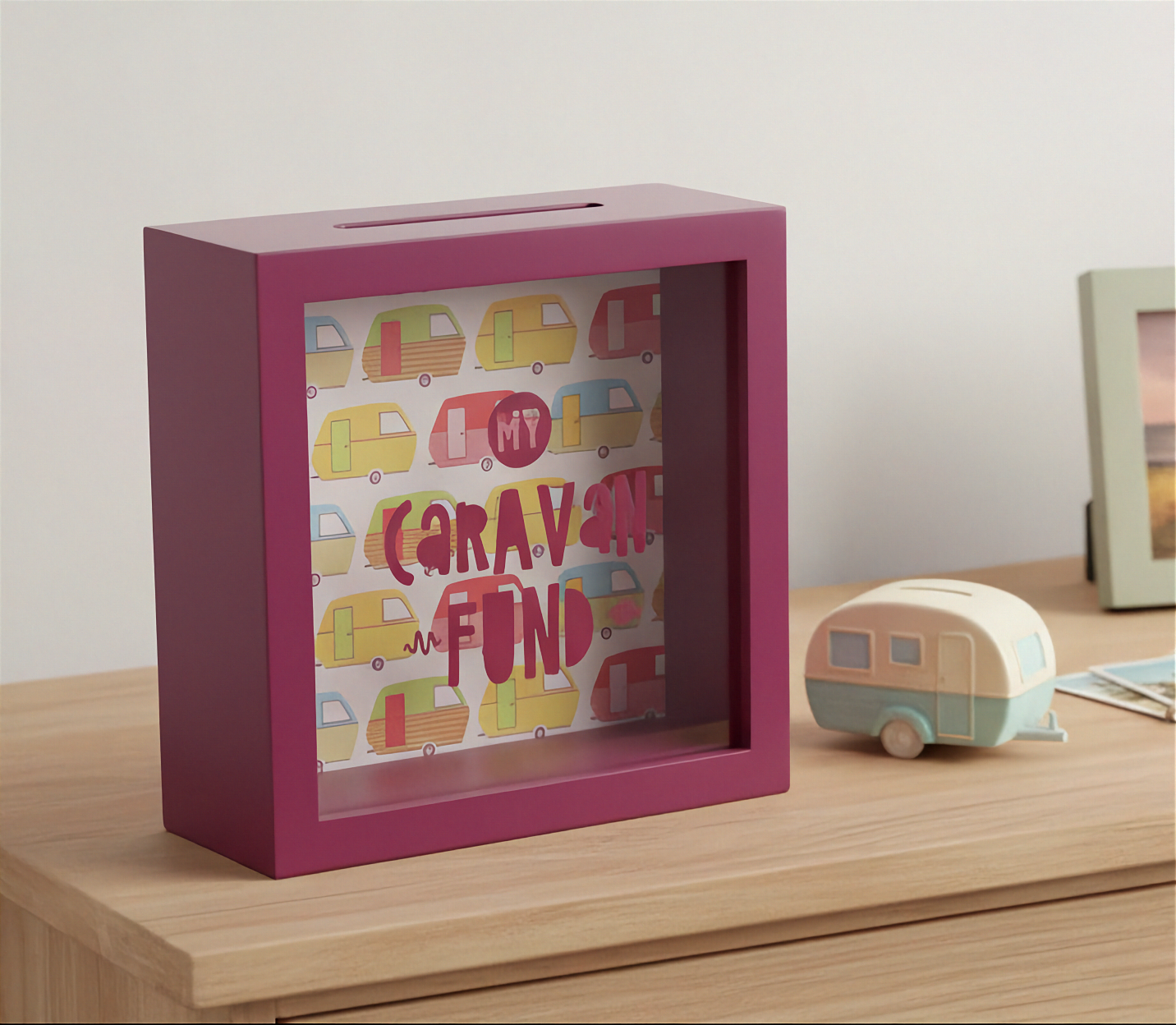 Red money box with 'My Caravan Fund' design on a wooden surface.
