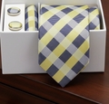 Plaid blue and yellow tie and cufflinks set in a white box on a wooden surface