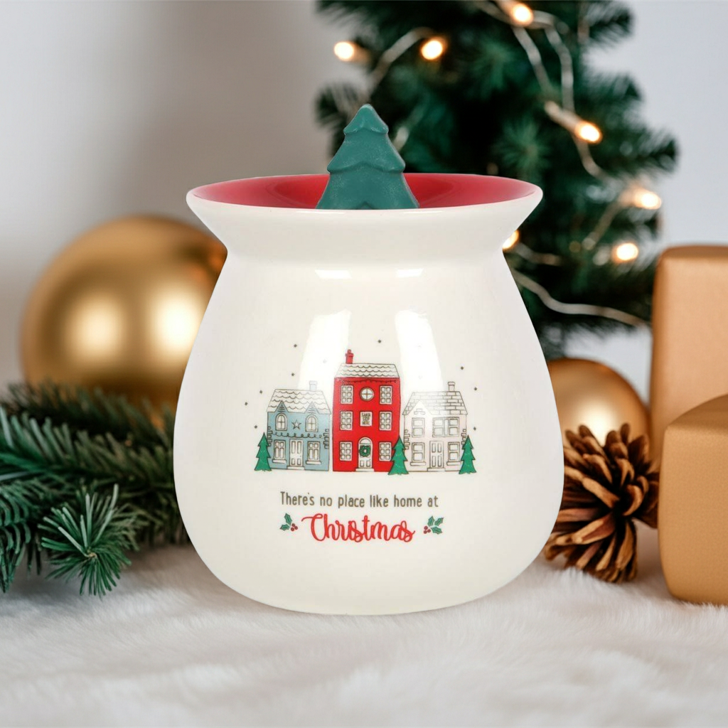Decorative wax warmer with Christmas design and tree on top, surrounded by festive decorations.