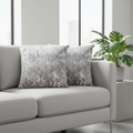 Gray sofa with decorative crushed velvet silver cushions and a plant in a modern living room.