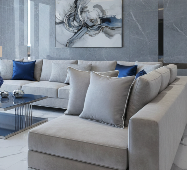Modern living room with a gray sectional sofa, blue and gray cushions, and abstract art on the wall.