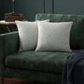 Green sofa with cream patterned cushions against a dark green wall.