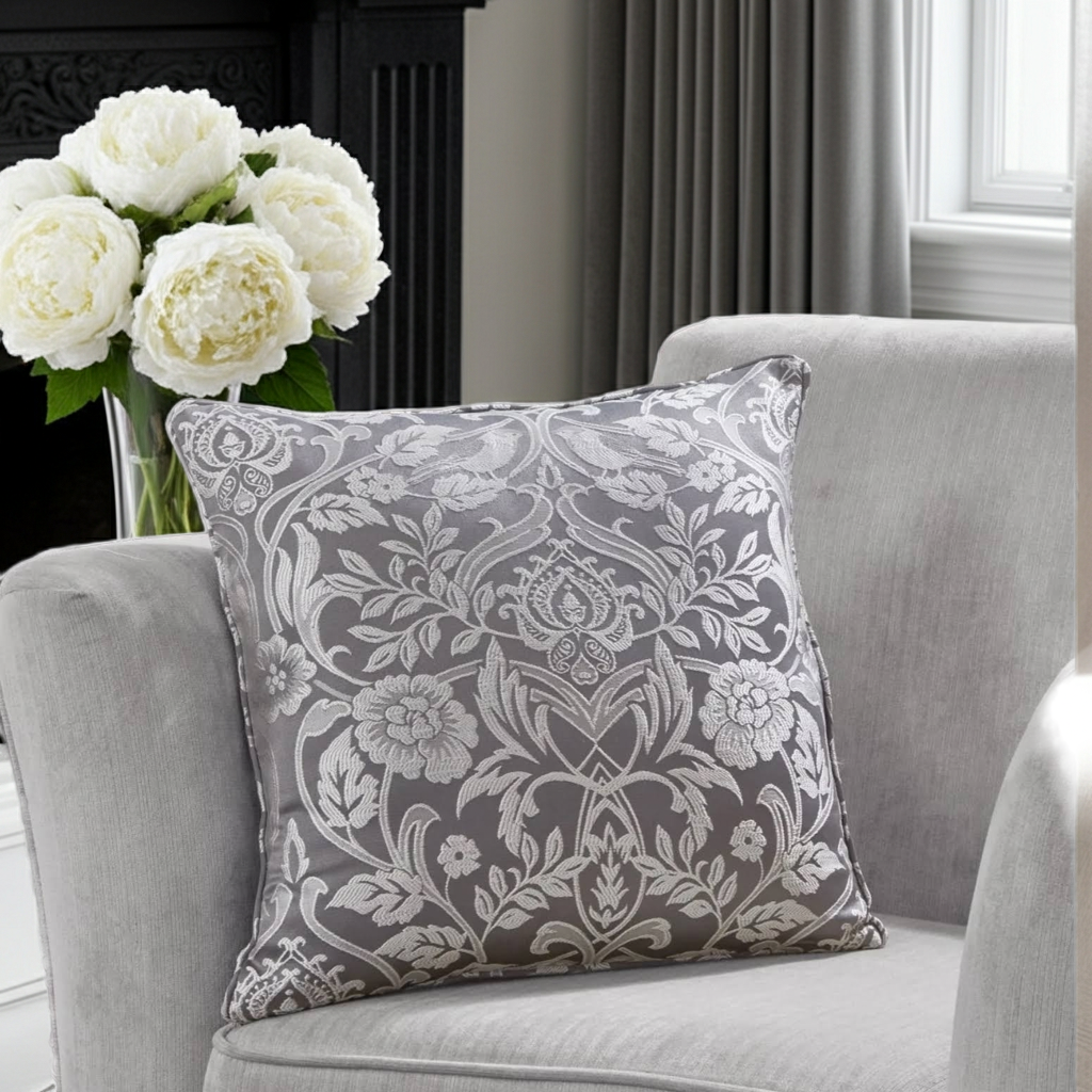 Decorative cushion with floral pattern on a gray armchair with white flowers in the background