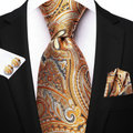 Black suit with a patterned orange and gray tie, matching pocket square, and cufflinks.