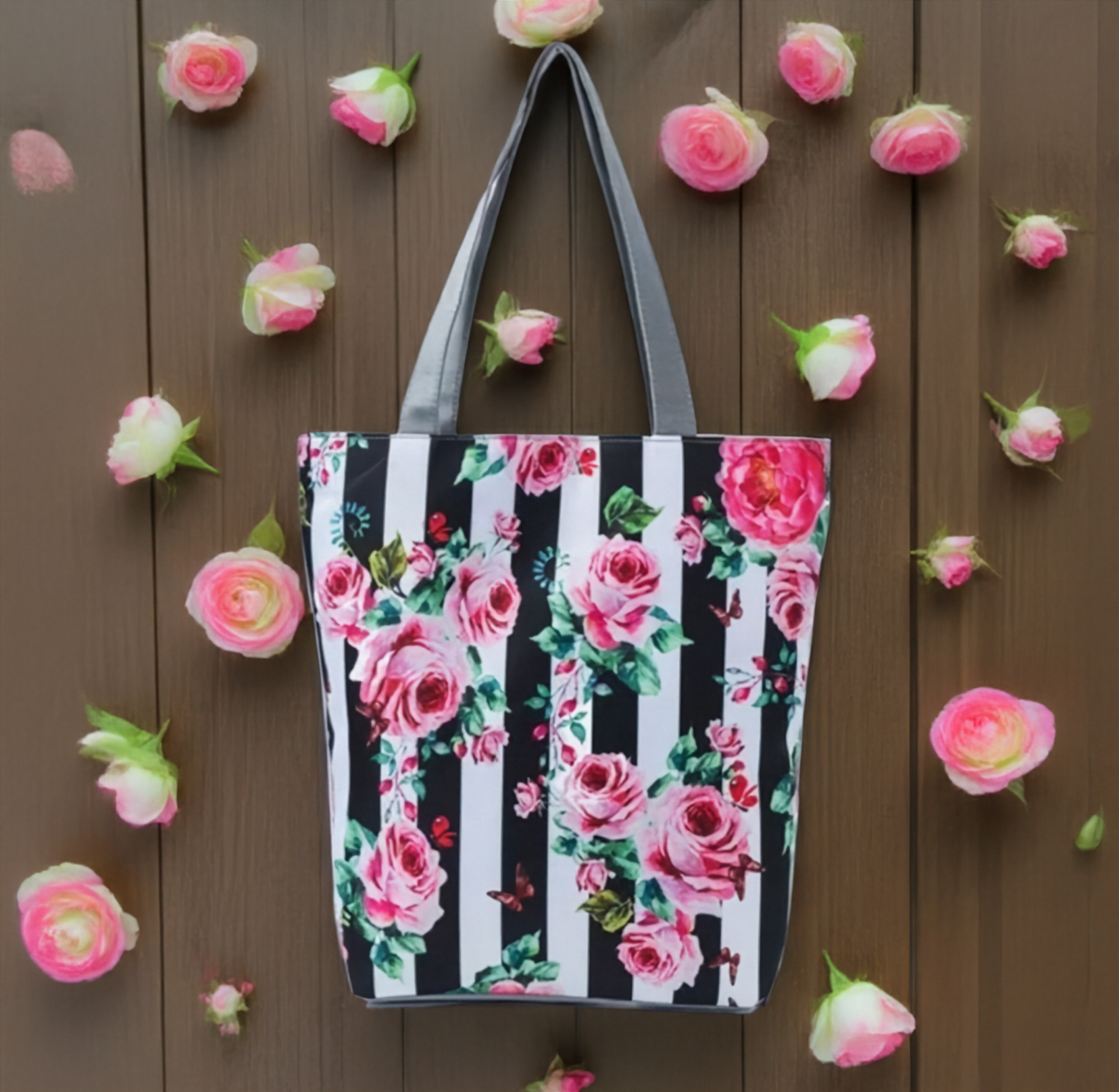 Tote bag with floral and striped pattern on a wooden background with flowers.
