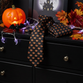 Black tie with brown pumpkin pattern on a black dresser with Halloween decorations.