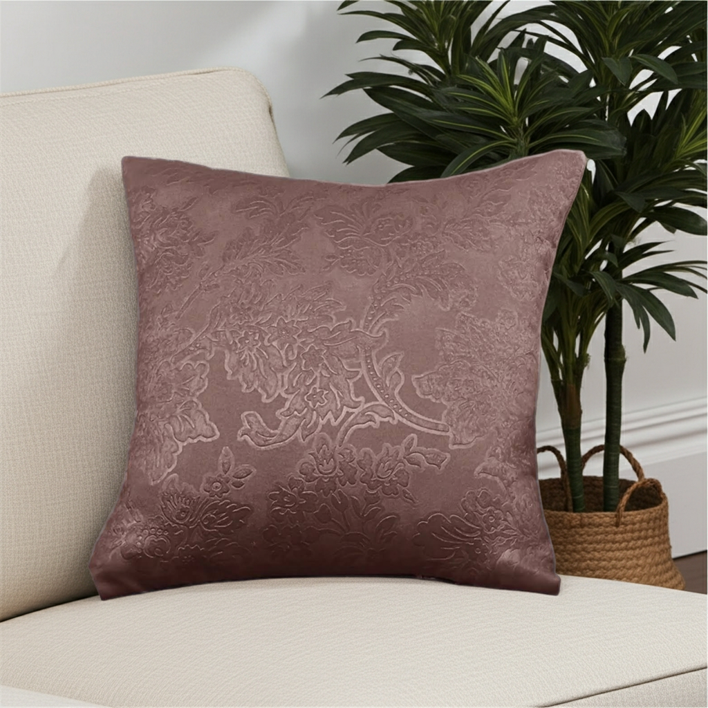 Decorative dusky pink cushion with floral pattern on a beige sofa next to a plant