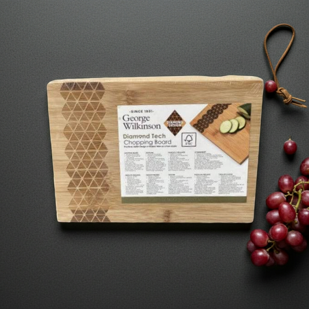 Wooden cutting board with brand label on a dark surface, accompanied by grapes.