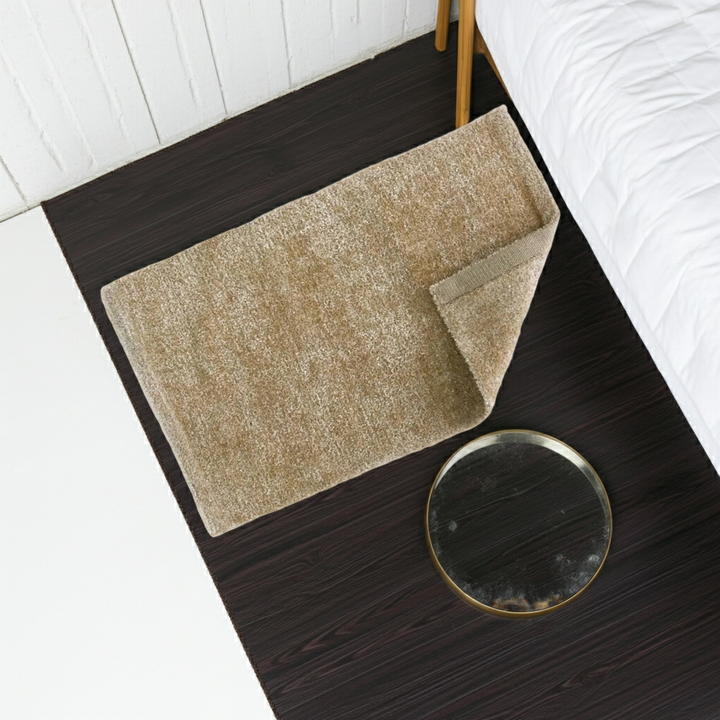 Beige rug on a dark wooden floor next to a bed