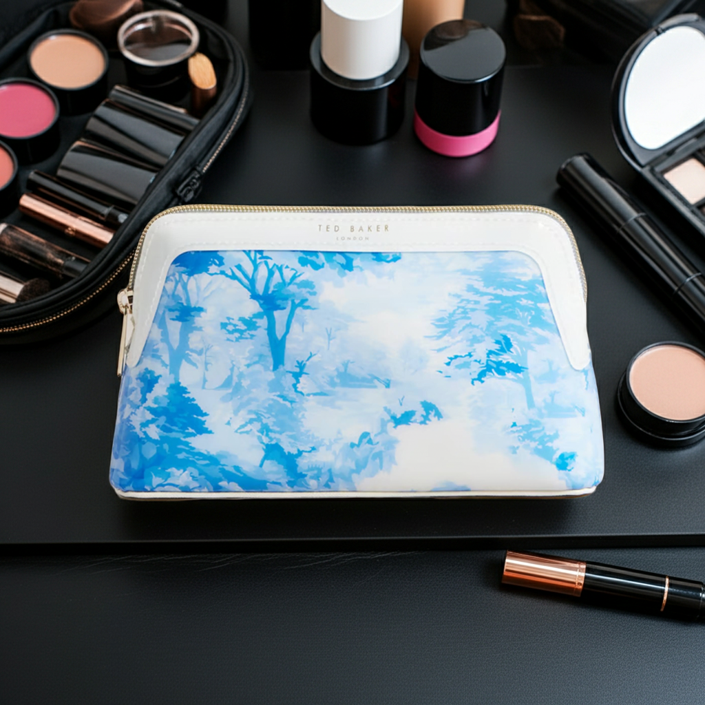 Ted Baker Makeup bag with blue and white design on a black surface with makeup items around