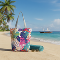 Colorful tropical patterned tote bag on a sandy beach with palm trees and ocean in the background.