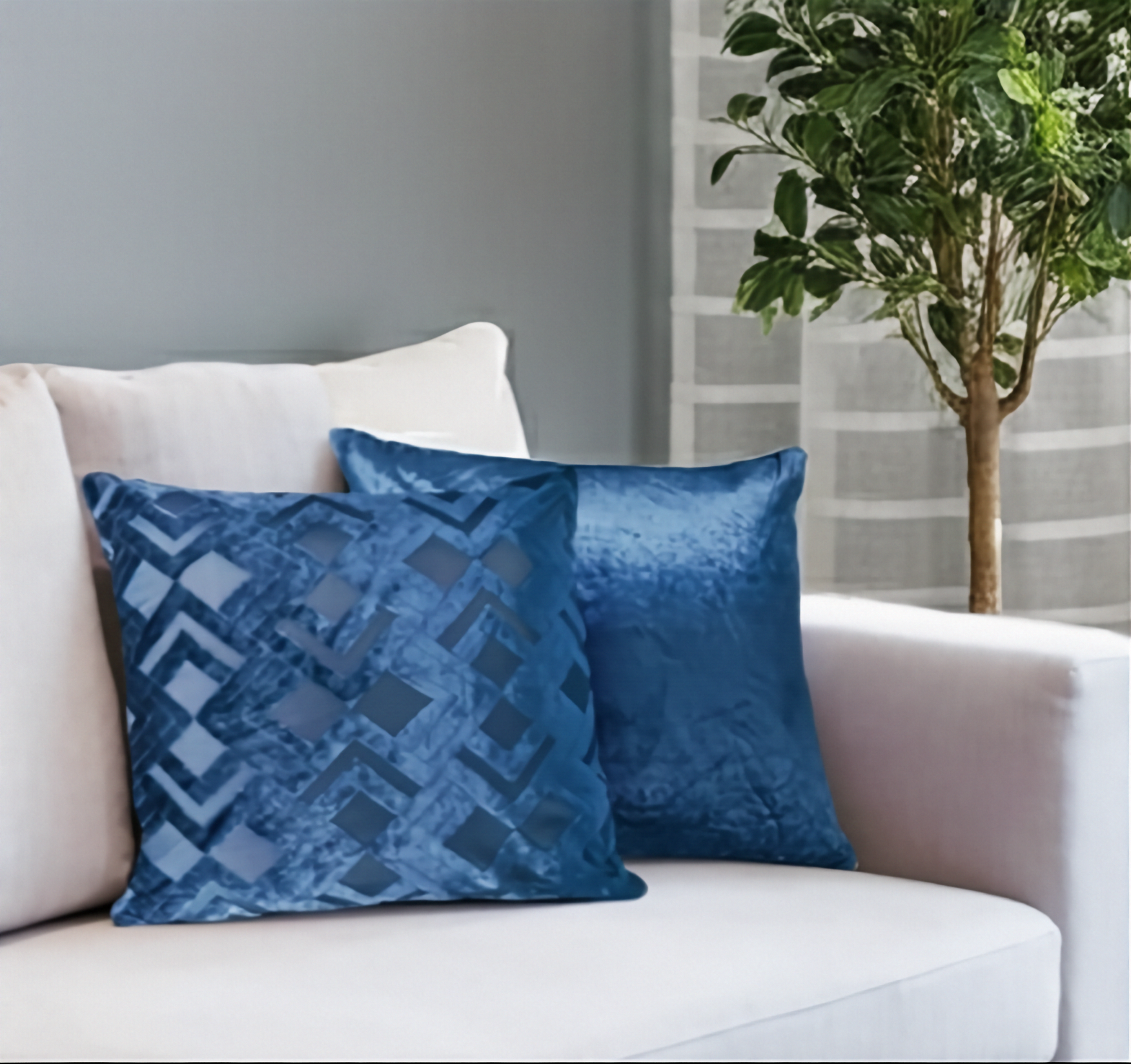 Blue patterned cushions on a white sofa with a plant in the background