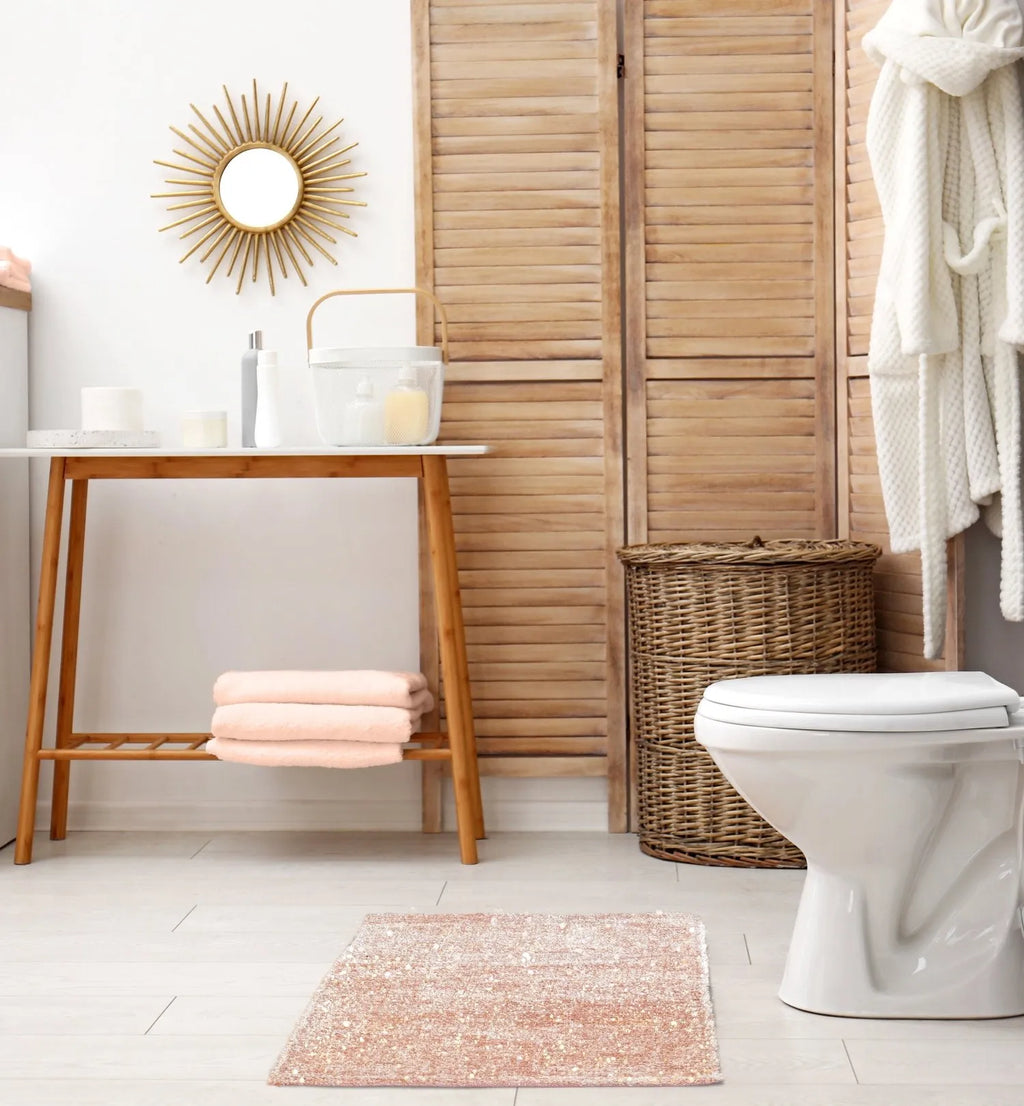 Bathroom interior with wooden vanity, toilet, and decorative elements showcasing pink sparkles rug.